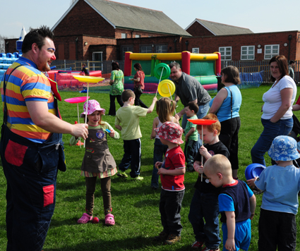 Curley Wurley Clown spinning a plate at a public event with members of the public doing various circus skills in Rotherham
